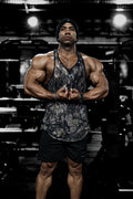 Muscular man wearing jed north graphic muscle stringer tank top in hunter camo with black shorts front view