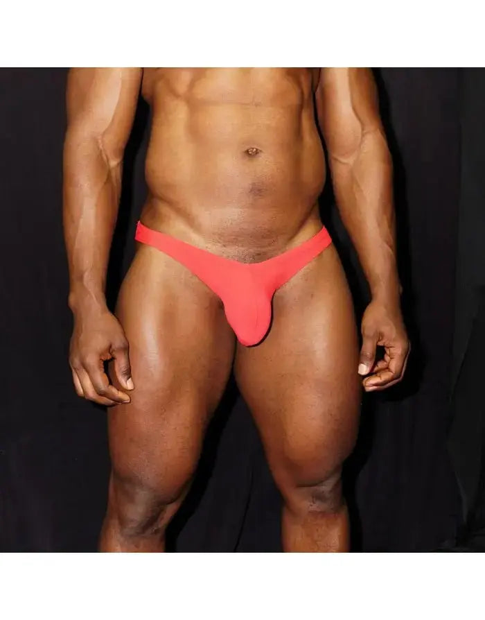Light red bikini briefs by Arroyman featuring a snug fit and minimal coverage shown on a model against a dark background.