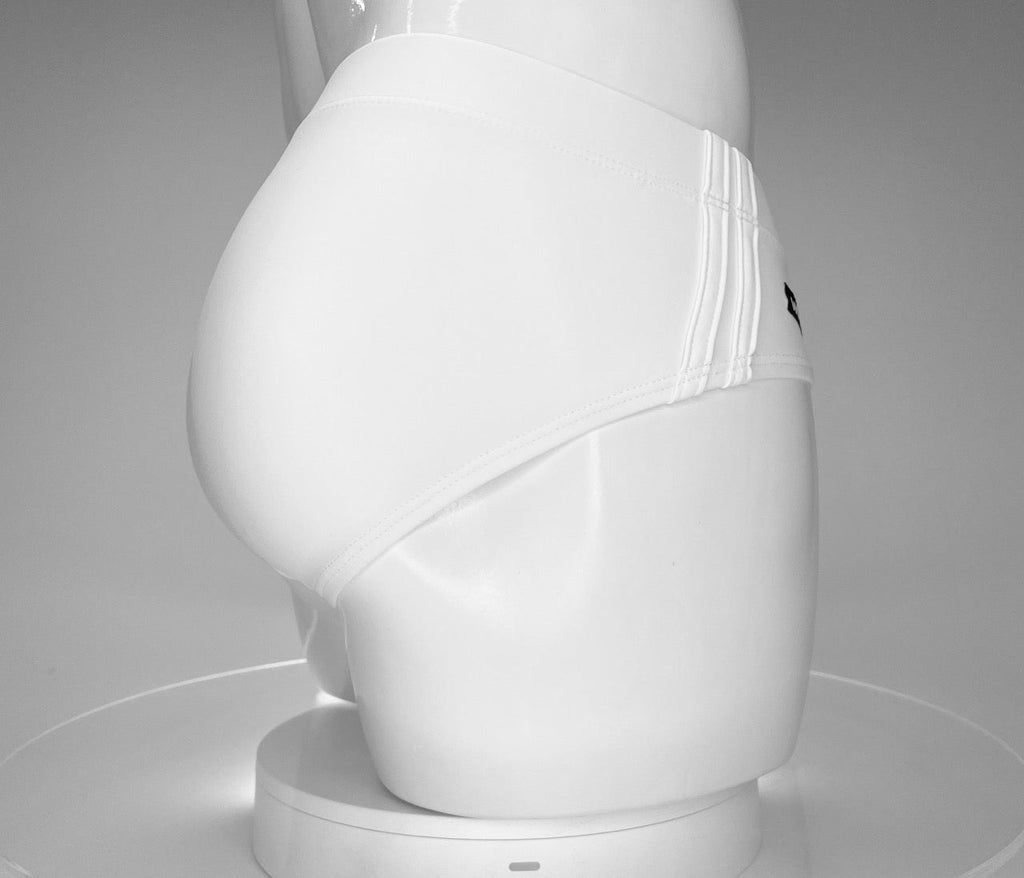 Side profile of white WildmanT swim brief on a mannequin, featuring triple-striped side panel details.