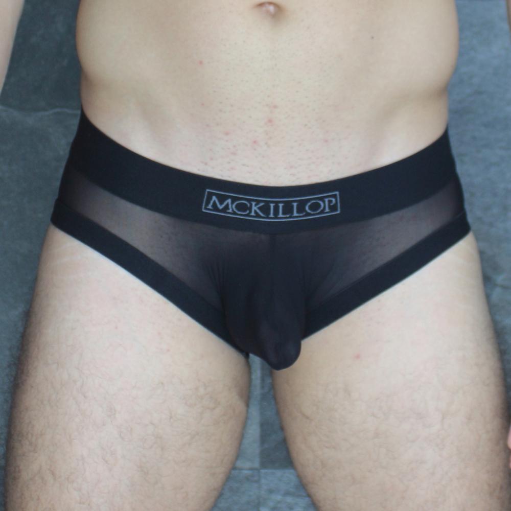 Black sheer mesh briefs with a solid black waistband featuring mckillop branding from the obus hoist brief ultra mesh line