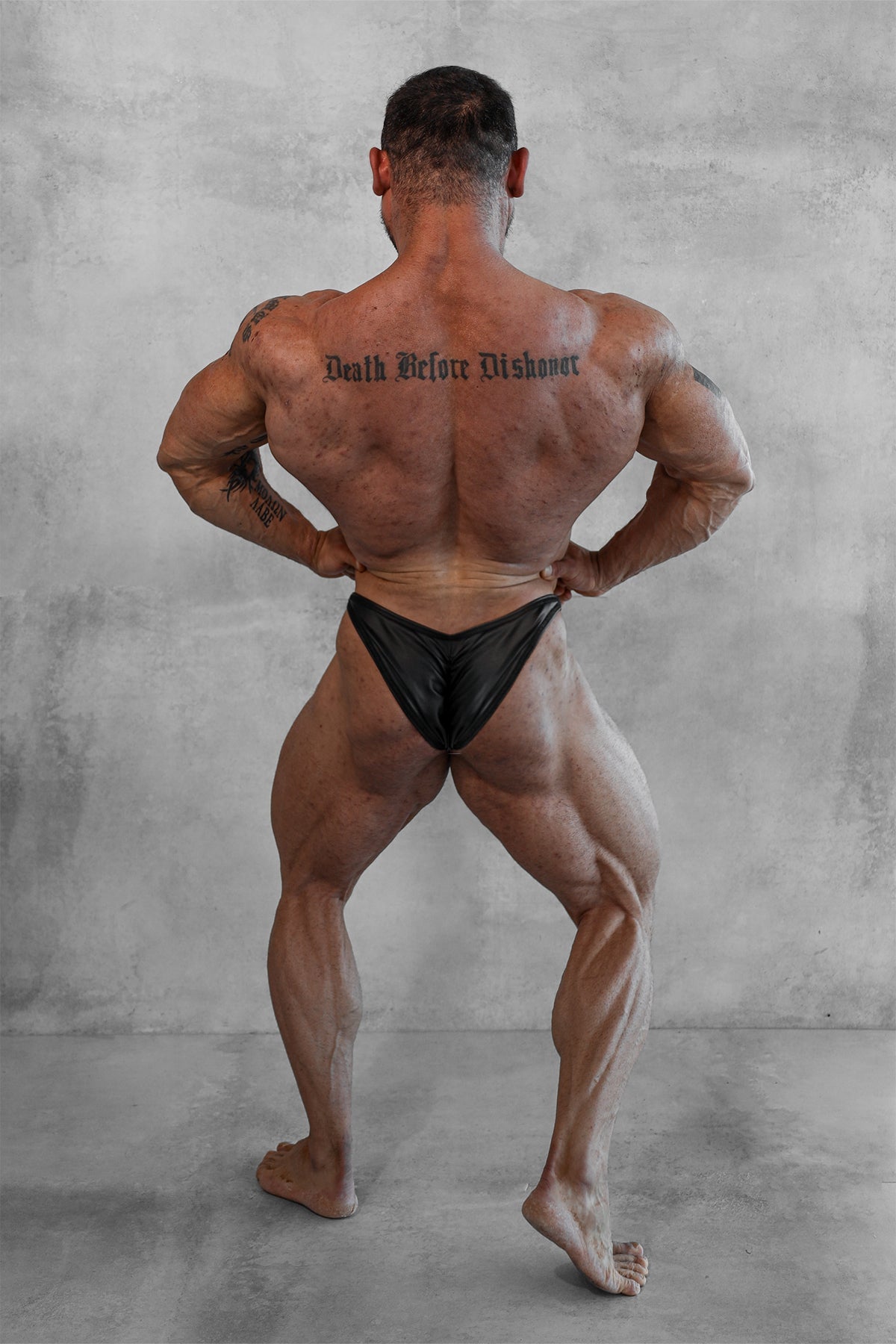 Men’s bodybuilding posing trunks in matte black featuring black form-fitting competition briefs shown from the back