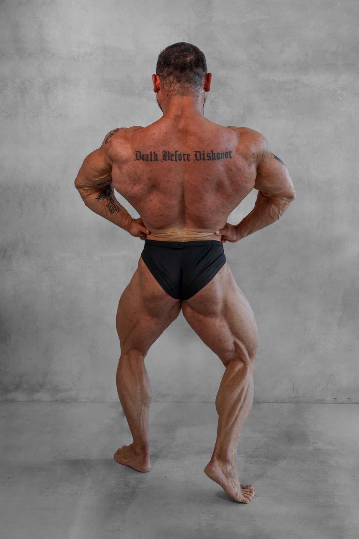 A muscular man wearing black men’s classic physique trunks with a 2 inch seam showcasing a sleek fit