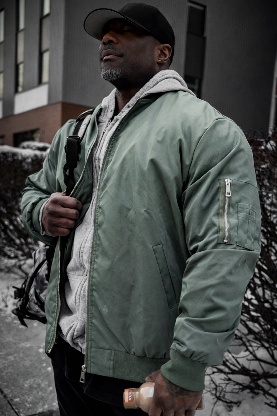 Men’s premium olive bomber jacket with gray fleece-lined hood and silver zippers for stylish warmth and comfort