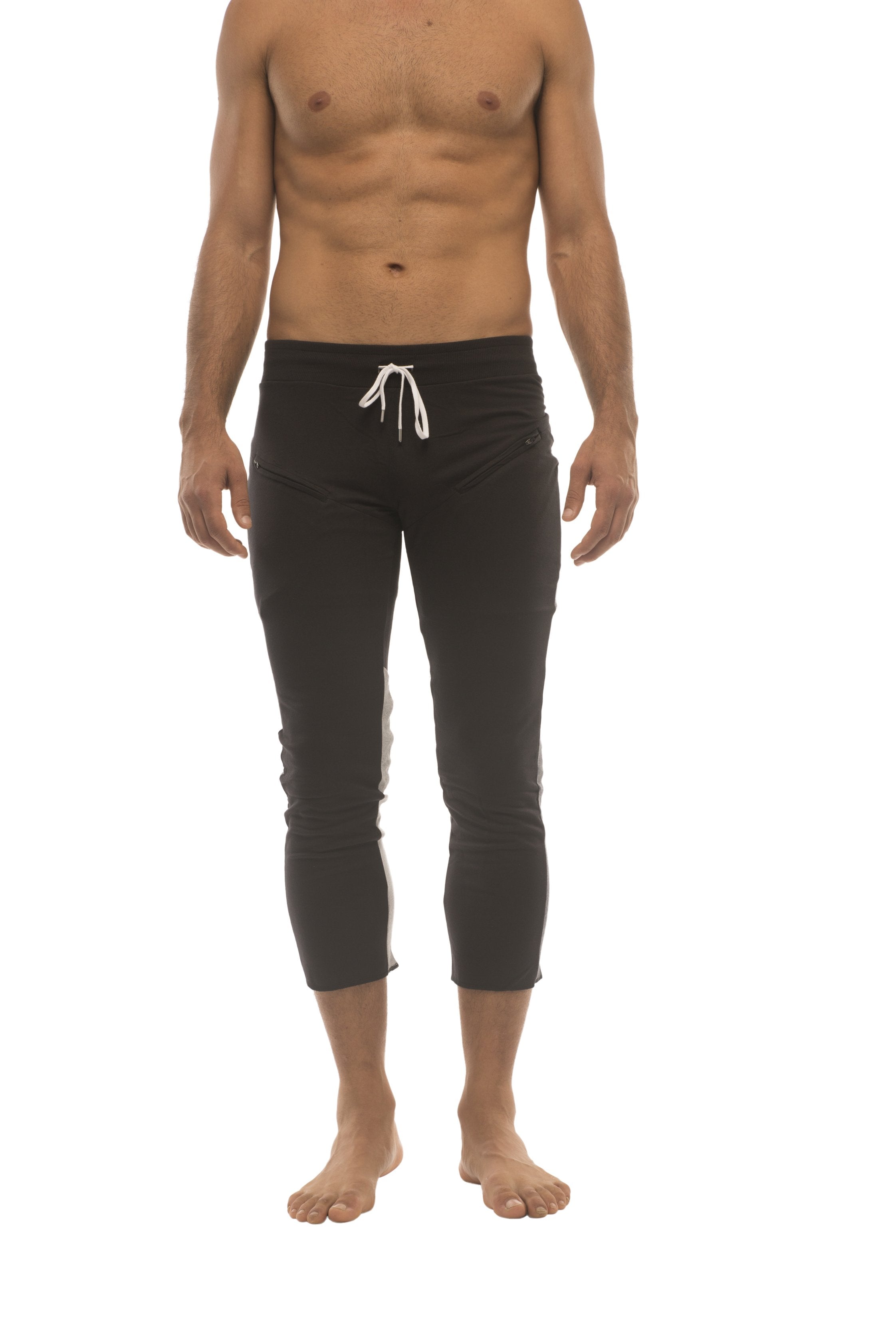 Mens black capri yoga pants with white drawstring waistband and subtle side stripes featuring zipper pockets