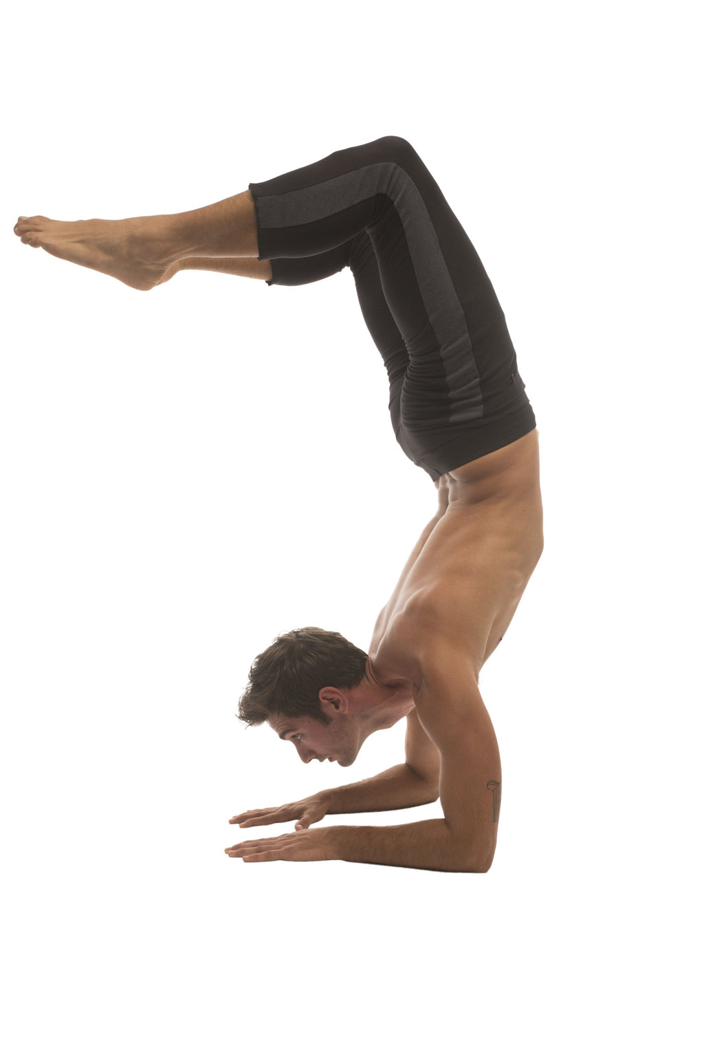 A man performing a handstand wearing mens black form-fitting 4/5 zipper pocket capri yoga pants