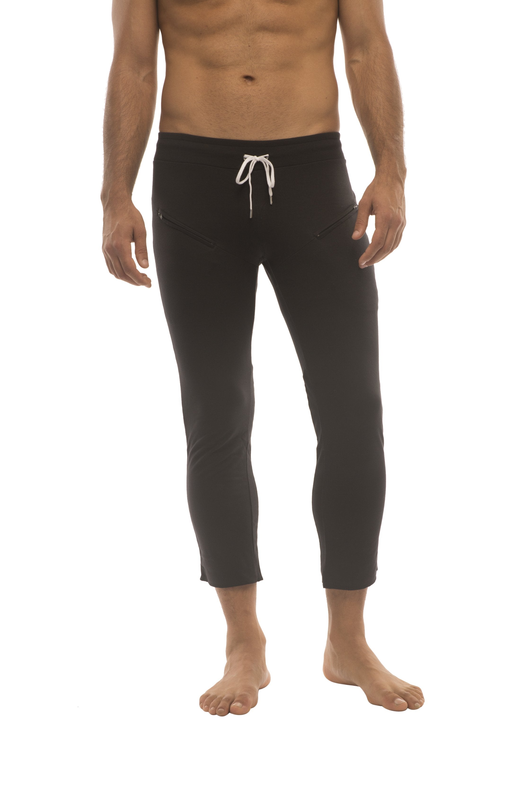 Mens solid black capri yoga pants with white drawstring waistband and 45 zipper pockets made from comfortable fabric