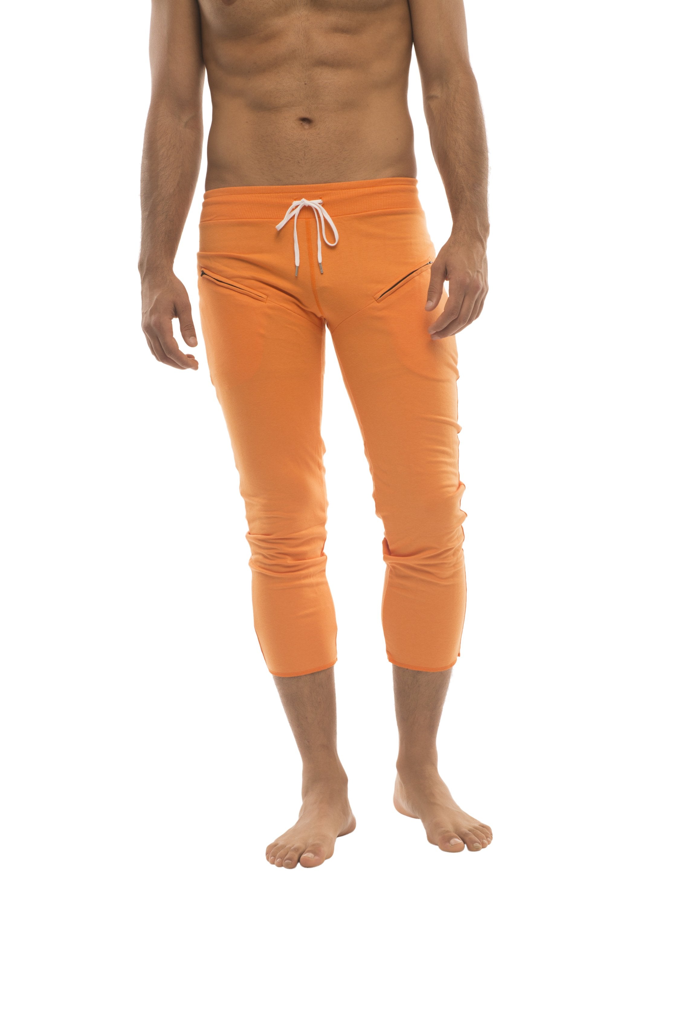 Mens solid orange capri yoga pants with white drawstring waistband and subtle side zipper pockets