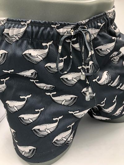 Black swim trunks with a repeating white whale line art pattern called Moby Dick shorts for casual beachwear