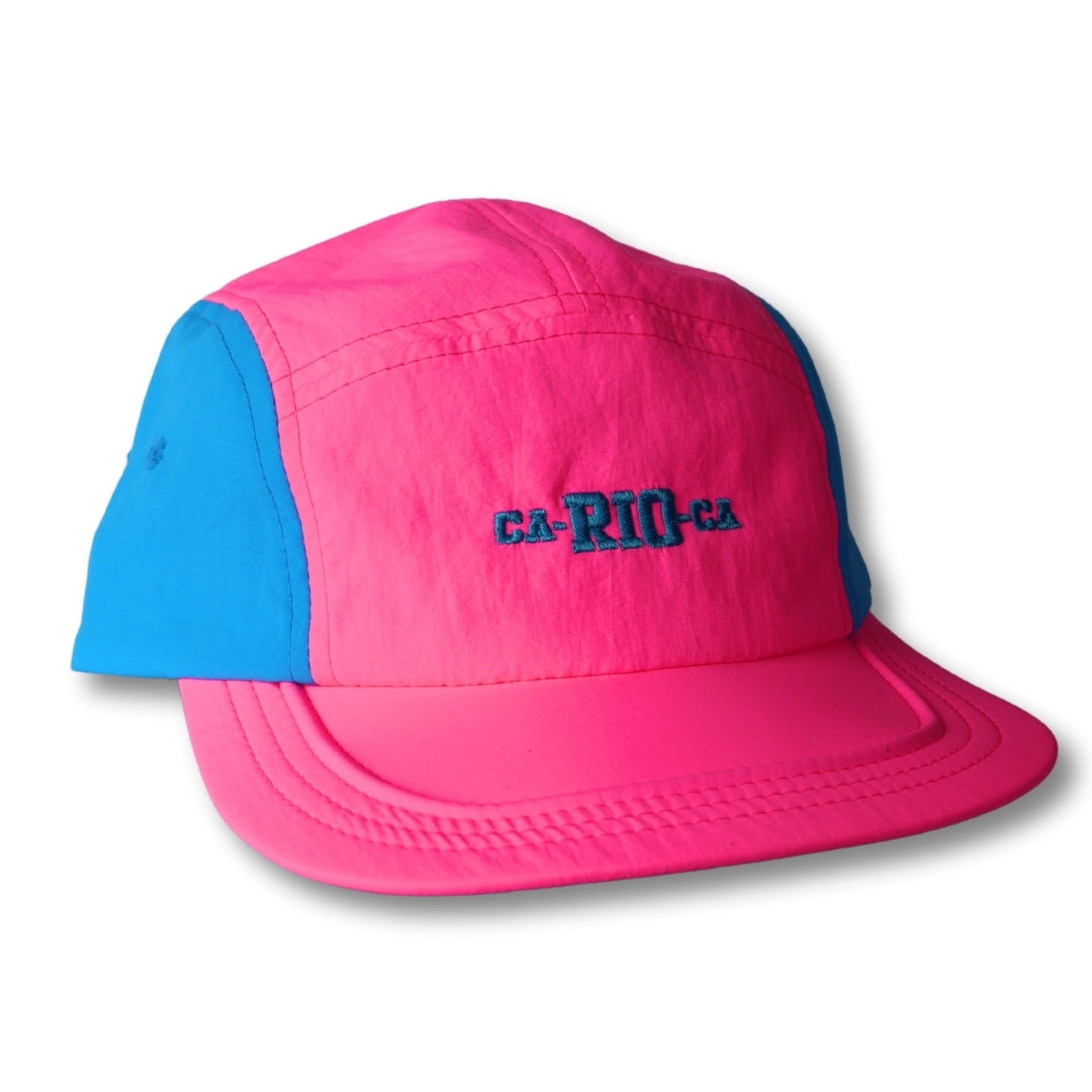 A vibrant pink and blue neon dream bike cap hat with ca-rio-ca embroidered in dark teal on the front panel