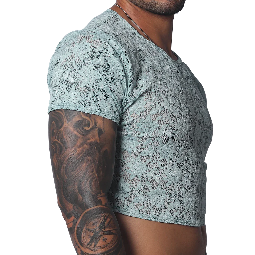 Sheer aqua blue floral lace crop top with short sleeves and a crew neck, worn by a man with arm tattoos.