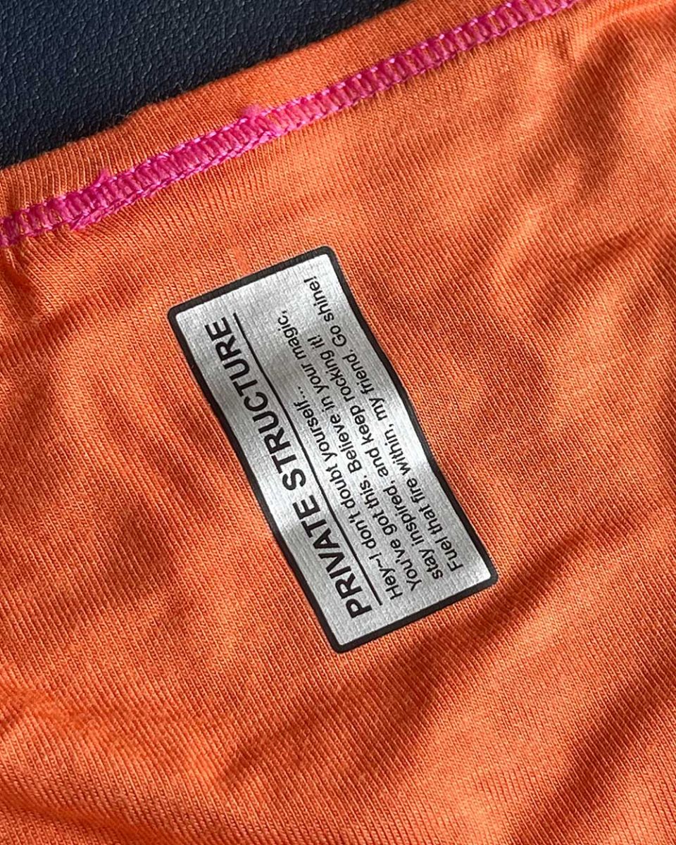 Orange private structure prime eutopia bikini brief with black and silver label stitched along the seam