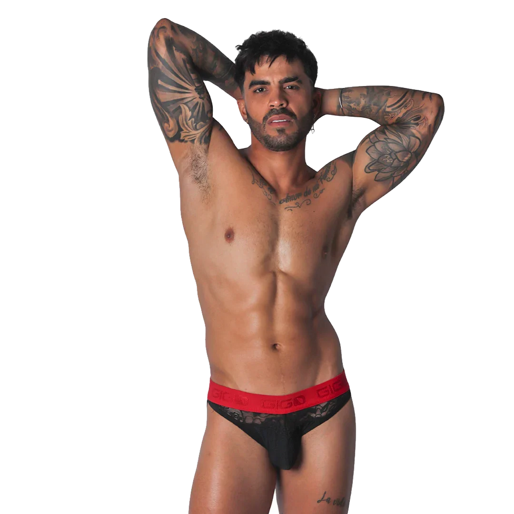 Black lace brief with a red elastic waistband featuring the Gigo logo, worn by a tattooed man.