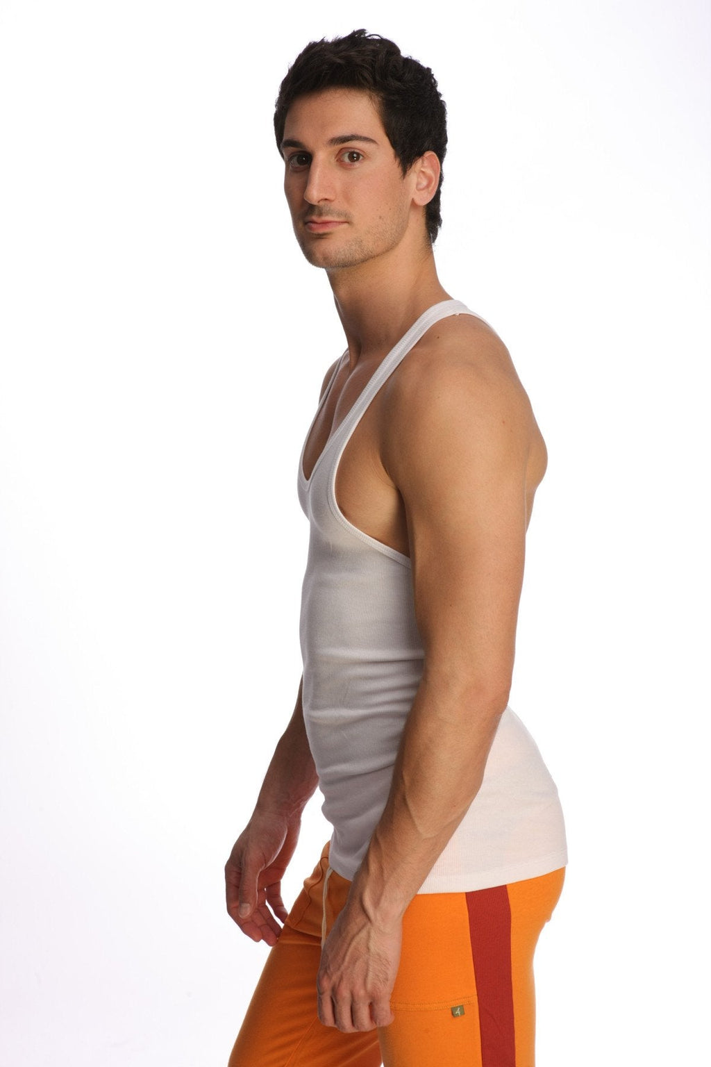 A man wearing a white racer-back yoga tank with thin straps and a v-neckline made of form-fitting material