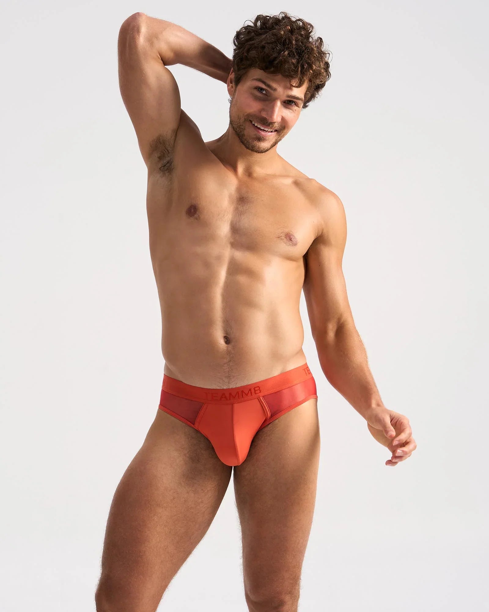 Bright orange sheer mesh briefs with solid waistband featuring amm logo from the score sheer brief collection