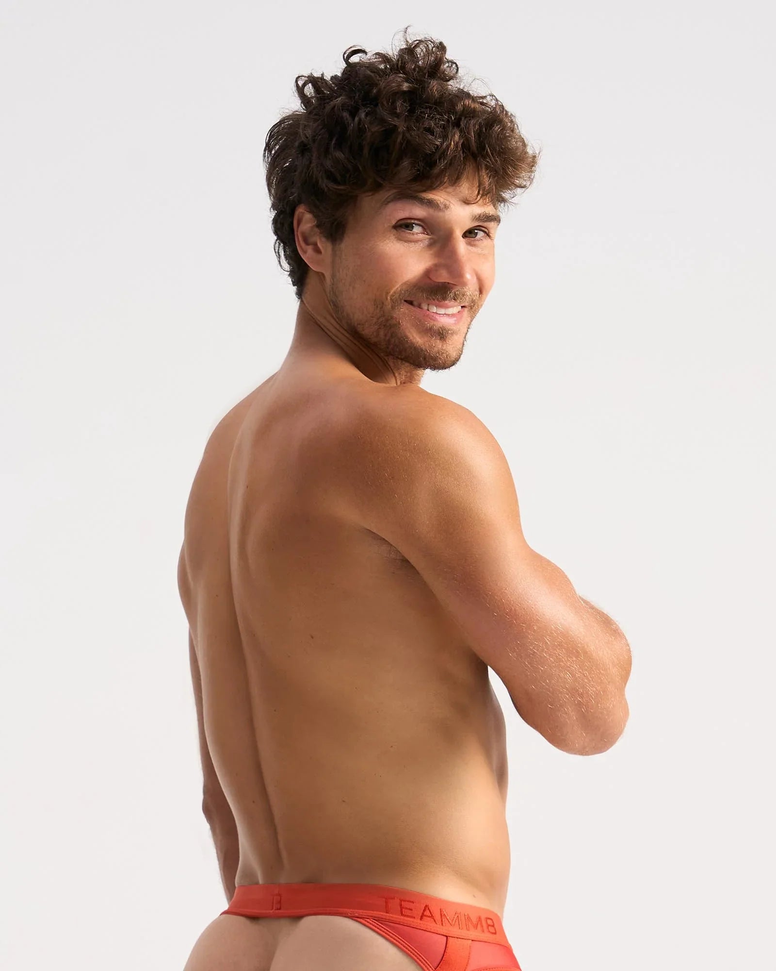 A man wearing bright red calvin klein sheer jock briefs with a visible logo on the waistband front view