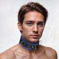 Man wearing a Strict Leather Deluxe black and blue locking leather collar with silver rings against a white background.