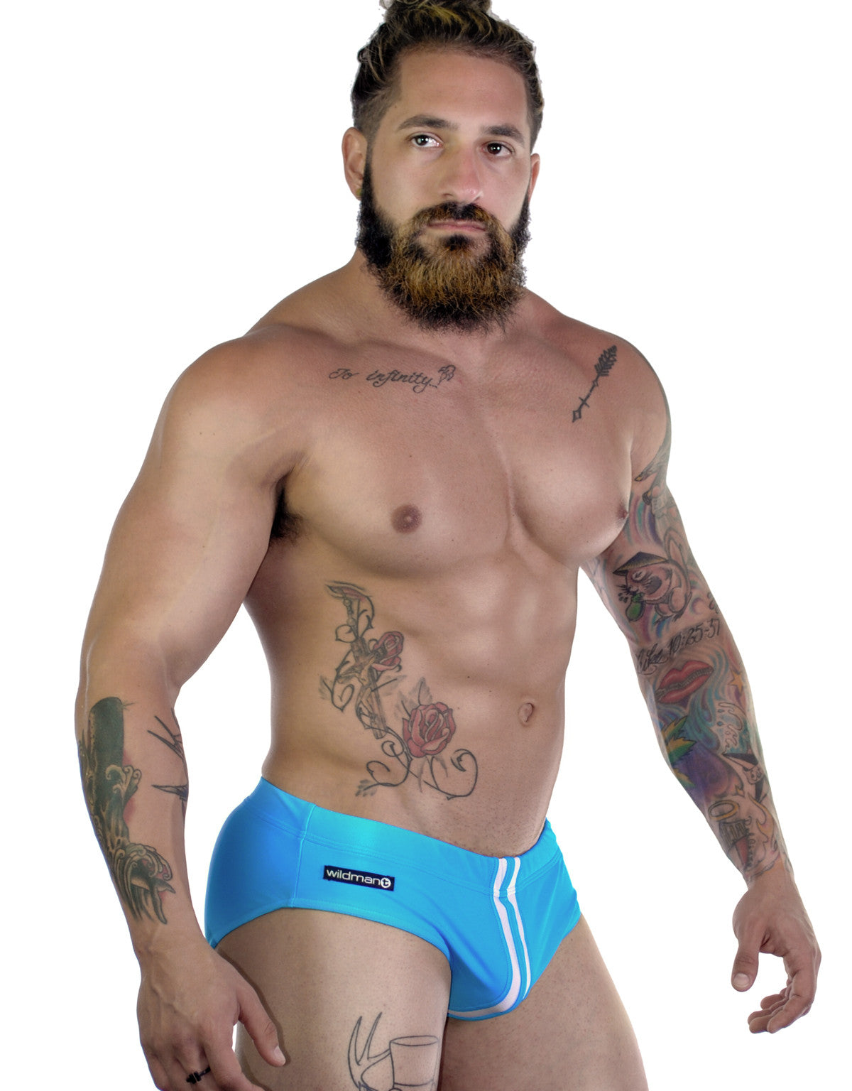 A tattooed man wearing a teal Sportivo Bikini with white vertical stripes and a WildmanT logo on the hip.
