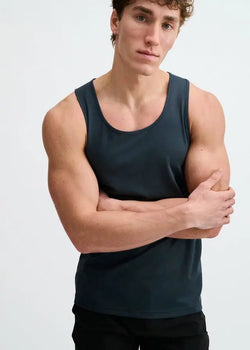 A man wearing the ST33LE Textured Stretch Mesh Performance Tank in Mariner, a dark blue sleeveless top.