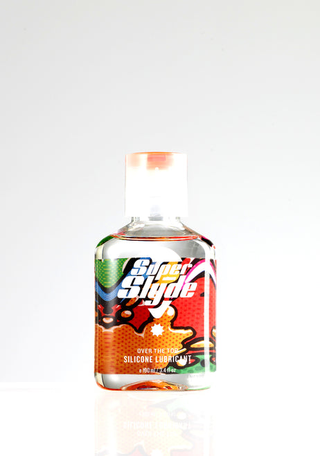 A clear plastic bottle of superslyde silicone lubricant with a colorful red orange green and black cartoon label