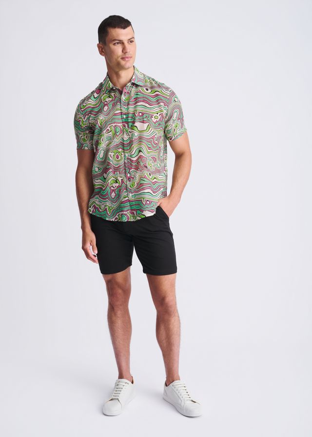 A man wearing a swirls lightweight cotton silk short-sleeved shirt with green pink and beige abstract pattern
