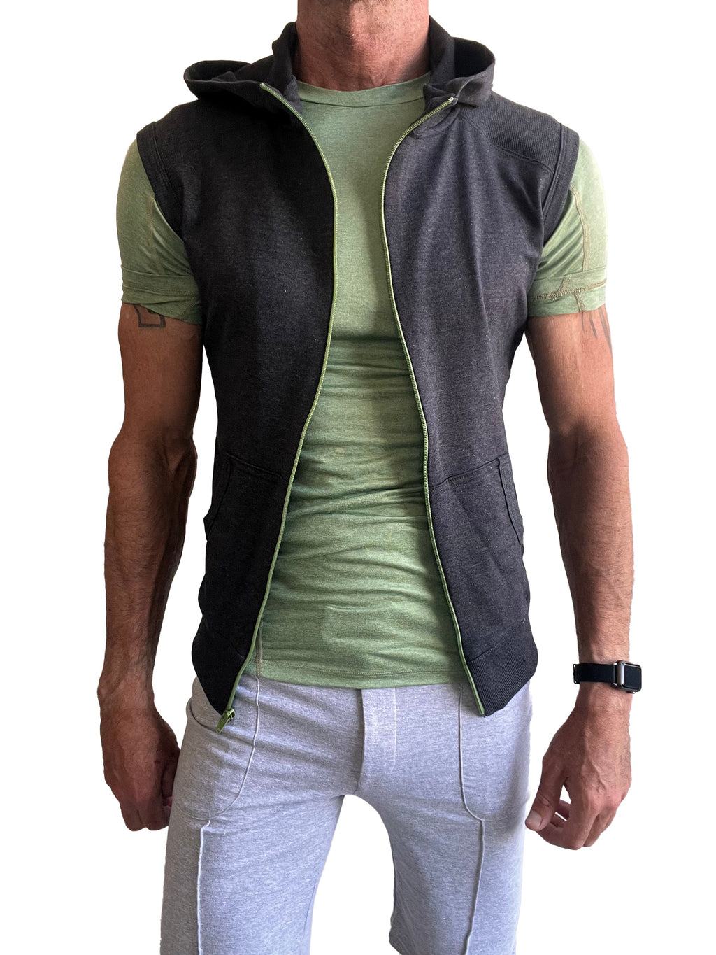 Dark gray sleeveless yoga hoodie vest with light green zipper and lining worn over olive green t-shirt for workout use