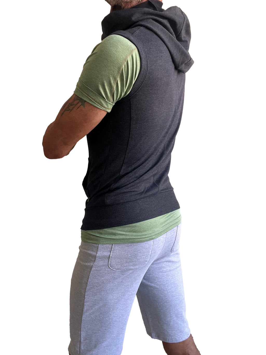 Black hooded sleeveless vest worn over green short-sleeved shirt shown from back in sleeveless yoga hoodie charcoal gray product