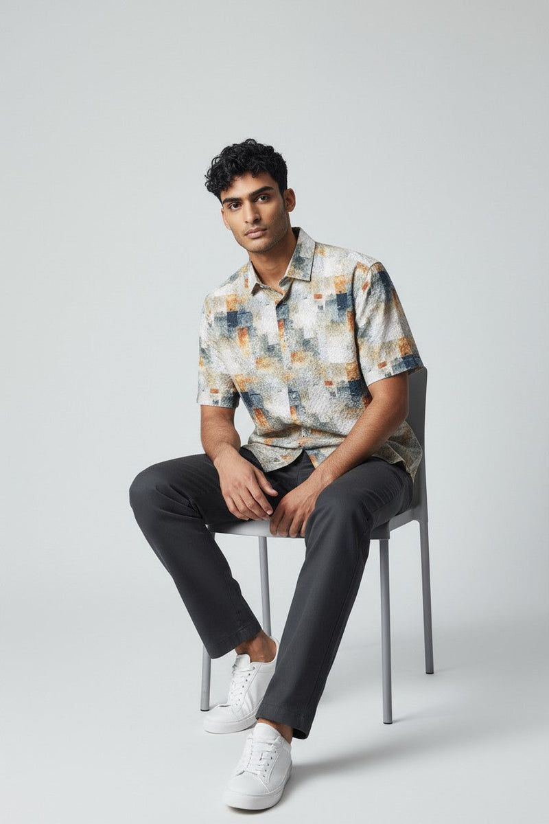 A man wearing a suslo crinkled fabric short-sleeved shirt with an abstract geometric pattern in beige gray and orange