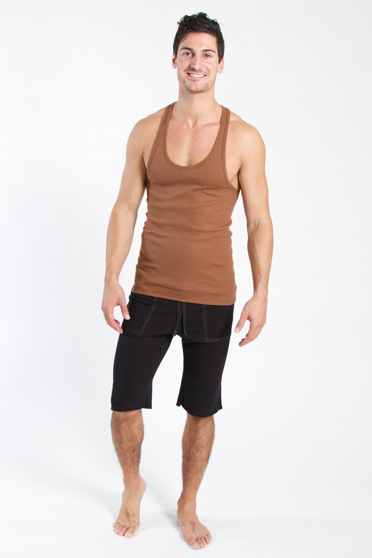 A man wearing a chocolate brown sustain tank top with scoop neckline and black shorts for casual wear