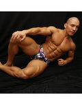 Men's bikini swimwear in navy with colorful sea flag print shown on a model by Arroyman.