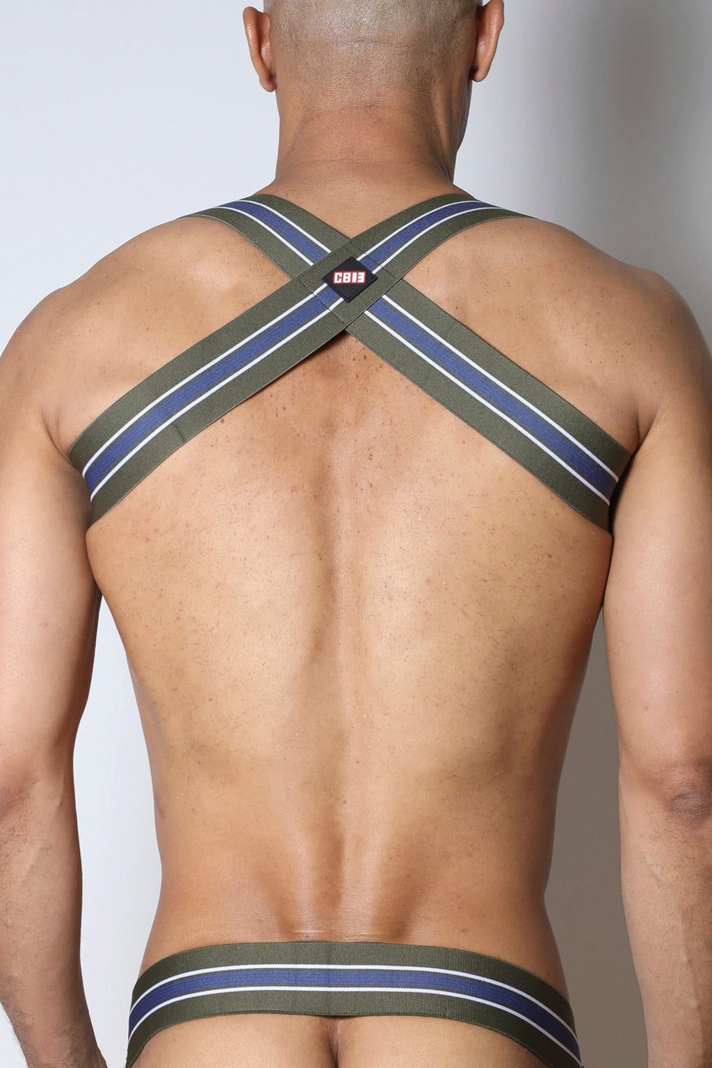 Back view of tight end elastic harness made of olive green and navy blue striped fabric with white trim and black logo patch