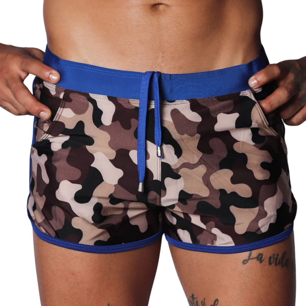 Camo print swim shorts with a blue elastic waistband, matching drawstring, and blue trim detail on a black background.