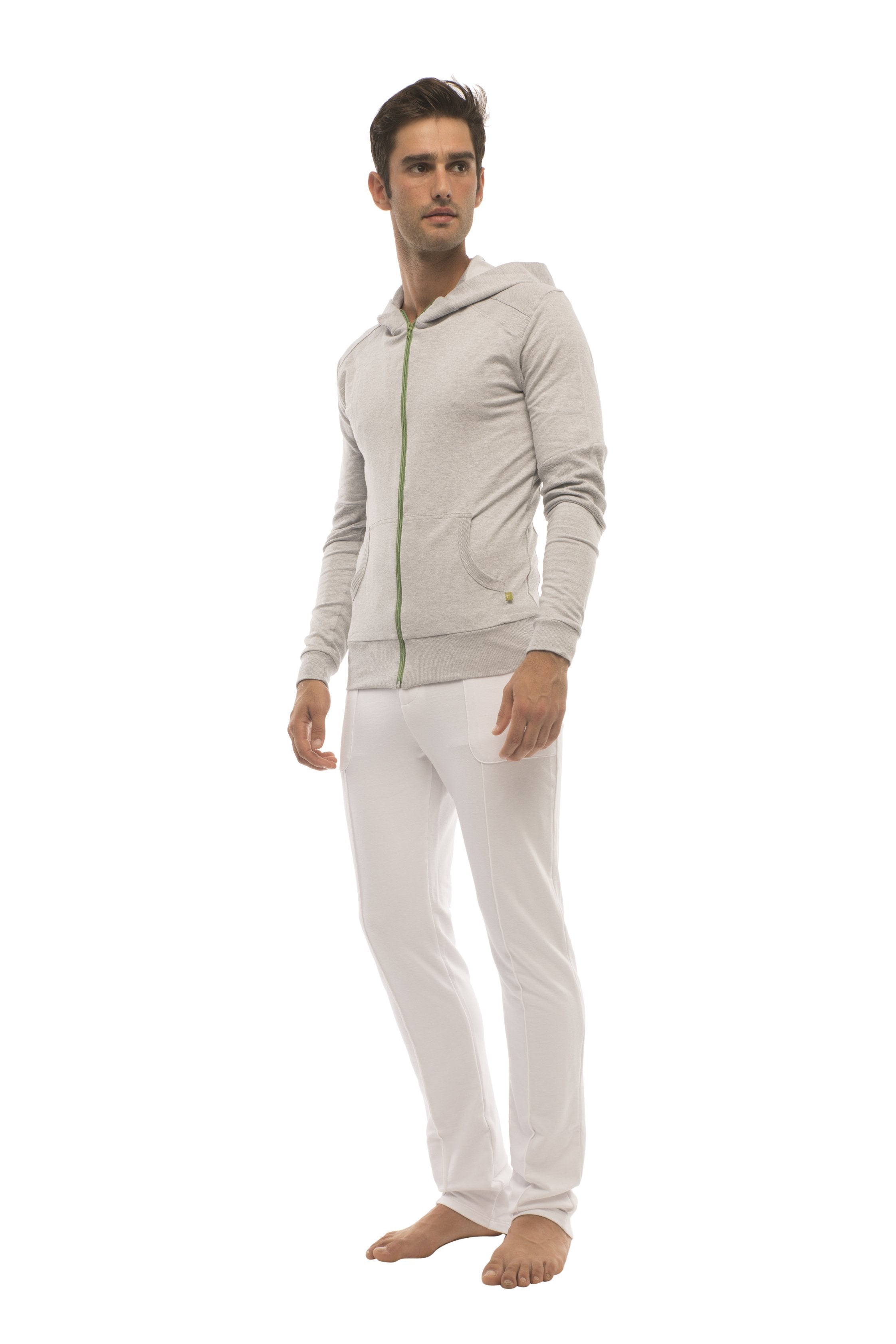A man wearing white tactical urban dress pant yoga pants with a light gray zip-up hoodie with green zipper accents