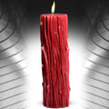 A tall vibrant red thorn drip candle with textured bark surface and a lit wick at the top