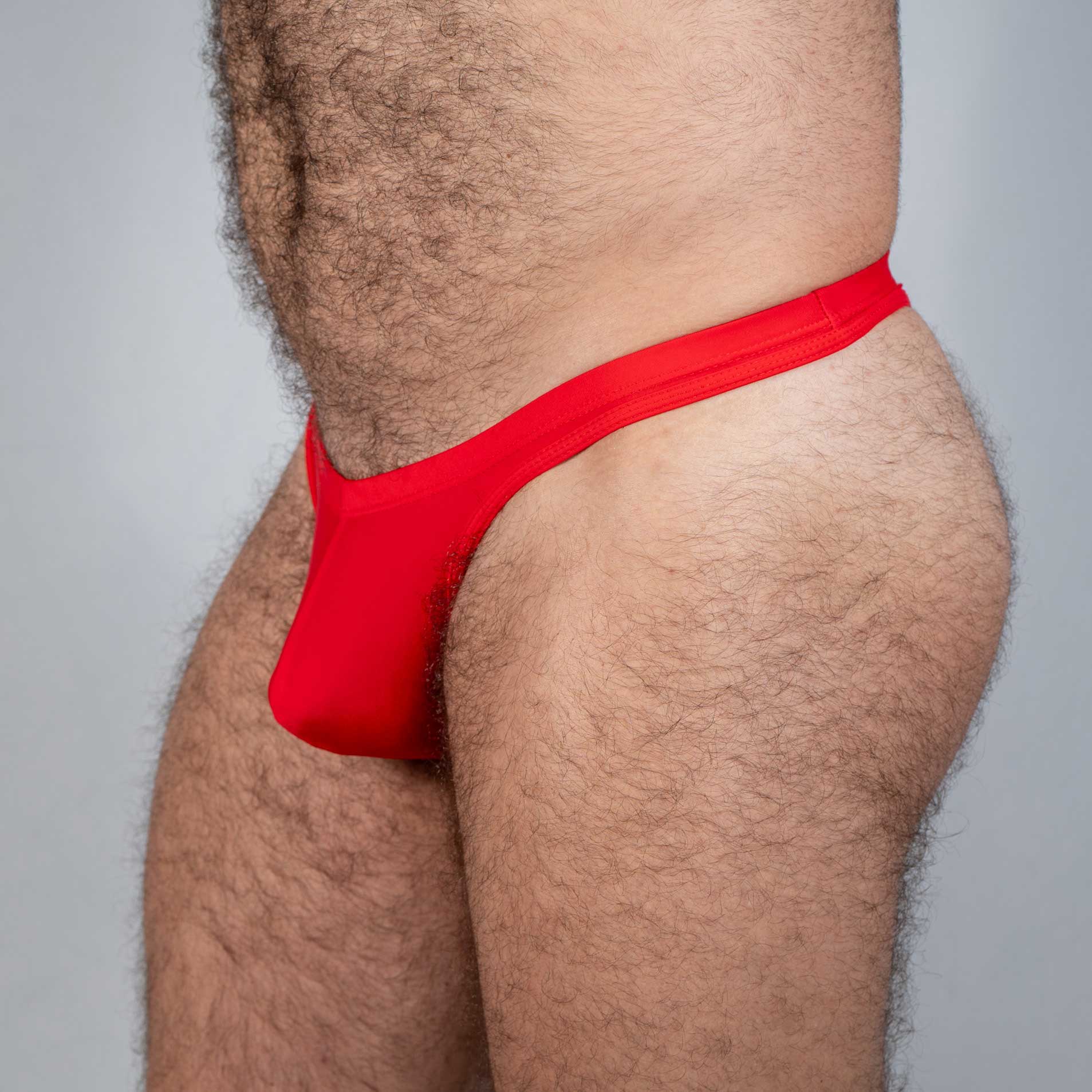 Red tulio swim thong made of smooth stretchy fabric shown from the back in a form-fitting solid design