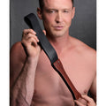 Black and brown leather flogger with metallic rivets designed for impact play in the wooden slapper collection