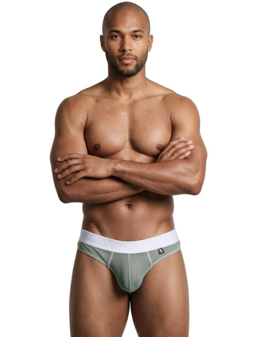 A shirtless man models green microfiber mesh thong underwear with a wide white waistband against a plain background.