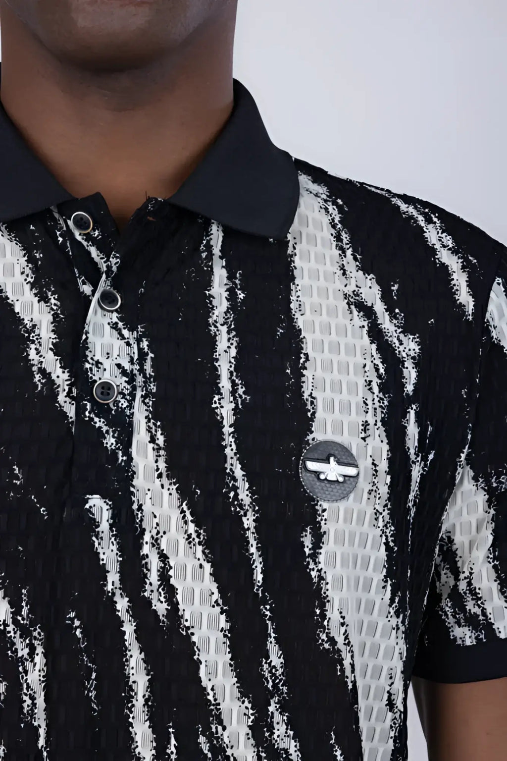 Black and white abstract polo shirt with textured fabric and circular logo patch on the chest