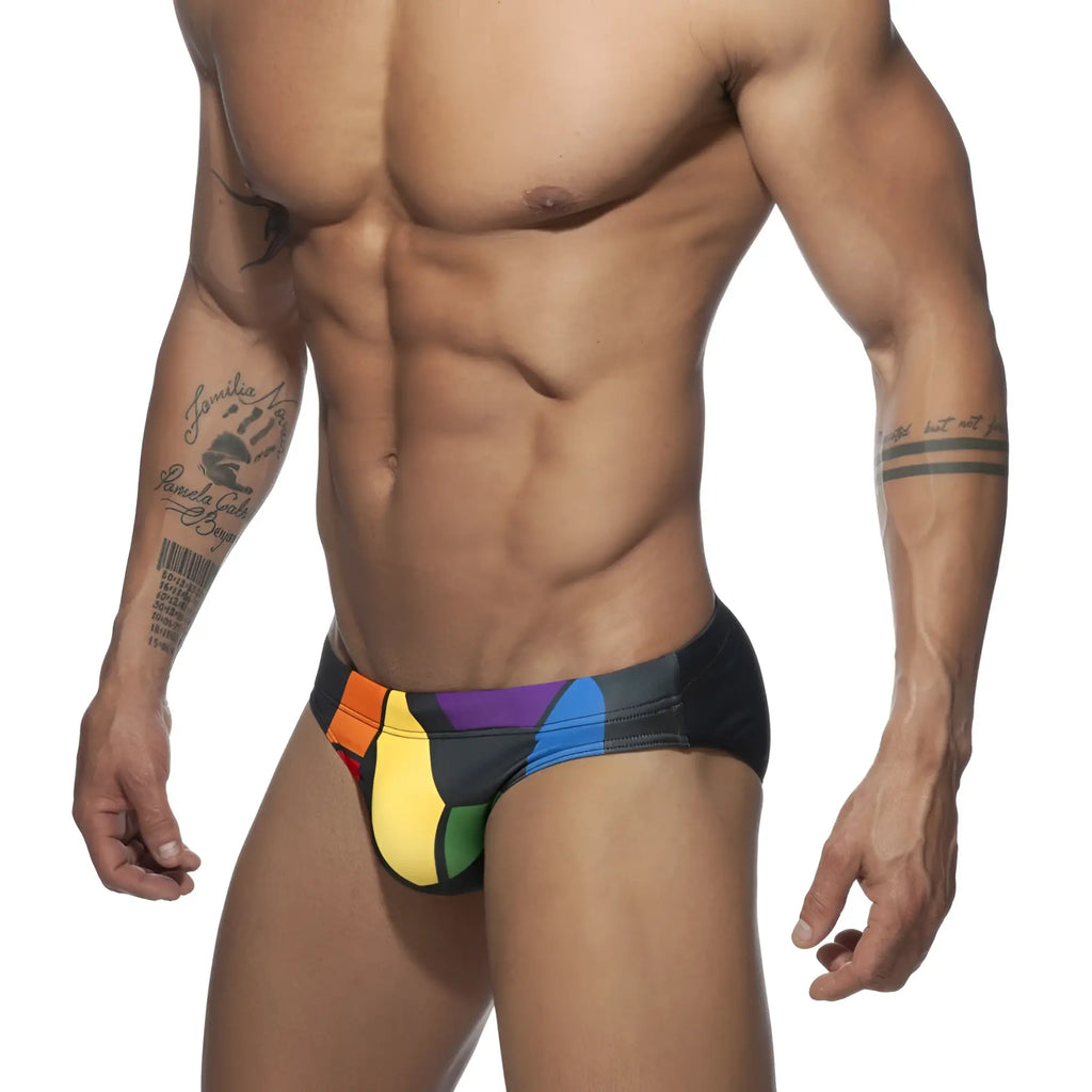Black swim trunks featuring a vibrant rainbow color block design for pride swimwear use