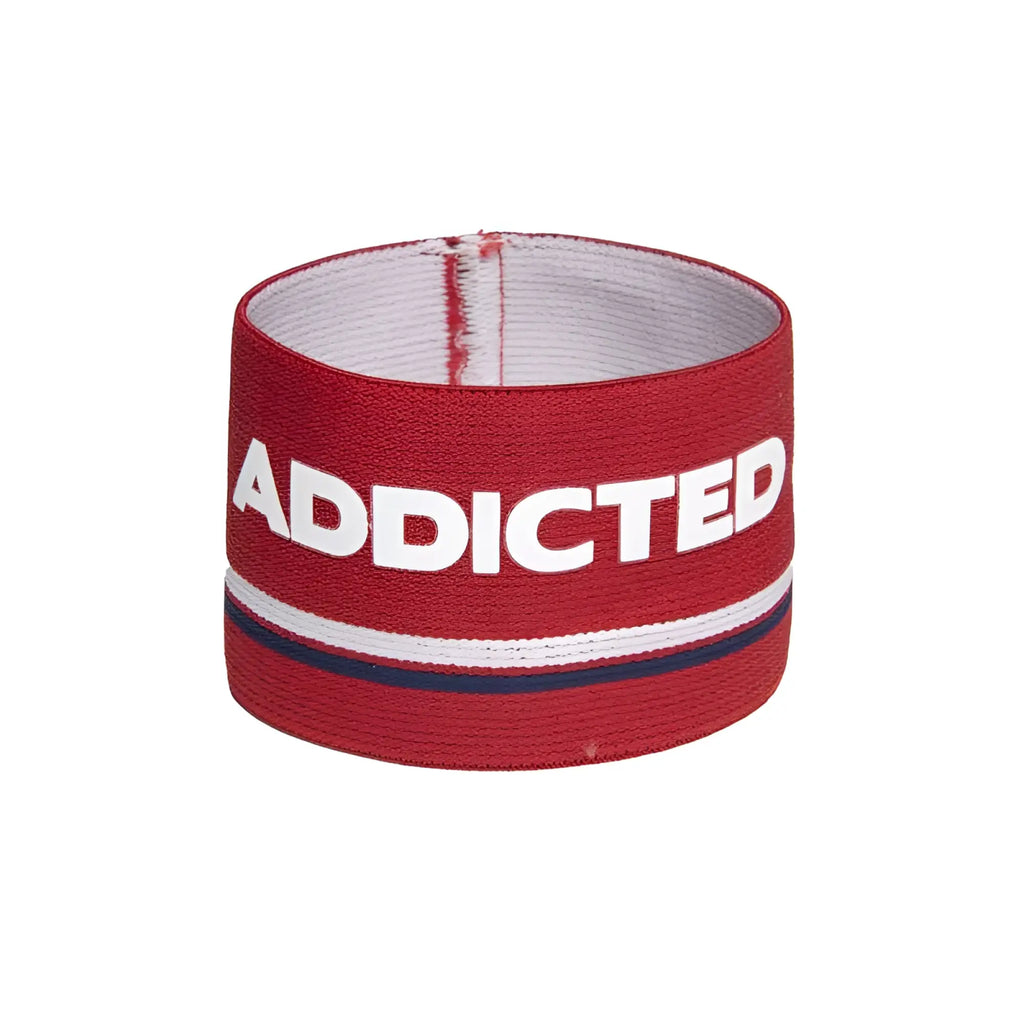 Red elastic bracelet with bold white addicted lettering and thin navy stripe on textured fabric surface size one size