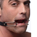 Strict Hook Claw Mouth Spreader: Silver metal hooks attached to a black strap, holding a person's mouth wide open.