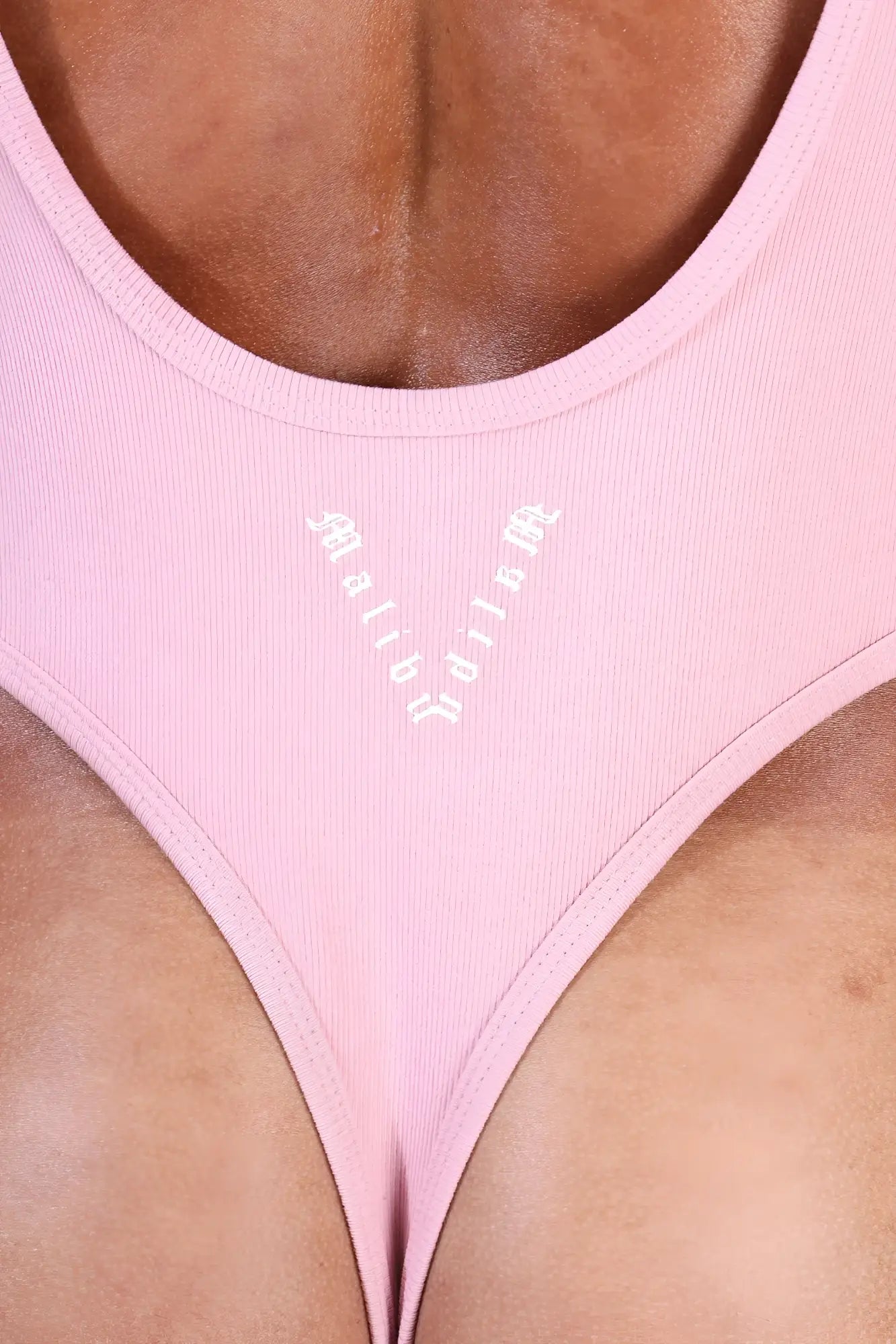 Pink ribbed fabric bikini bottom with v-shaped neckline and white mabbi branding from afterglow ribbed bodysuit blush pink