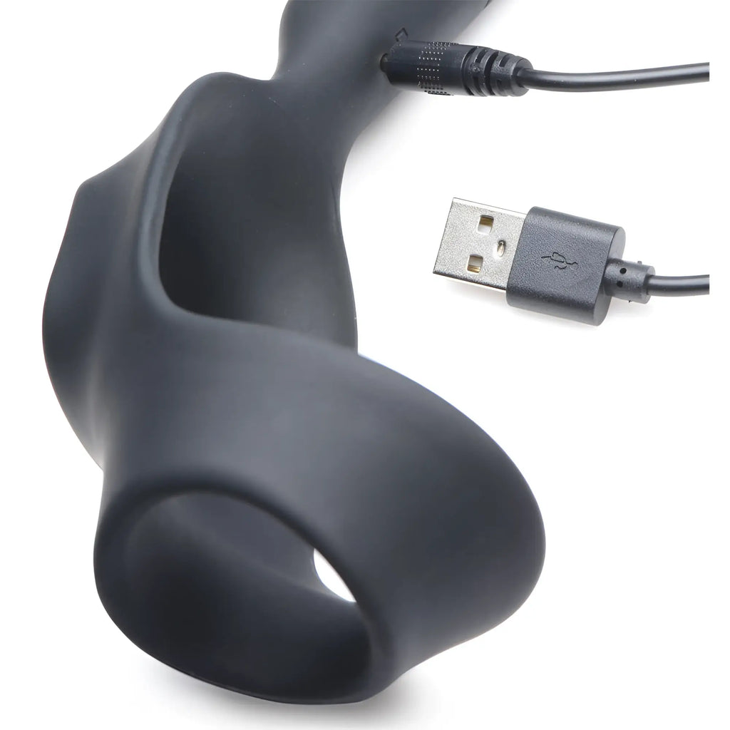 Black silicone Alpha Pro 10X P-Bomb vibrating cock ring and anal plug with its USB charging cable on white background.