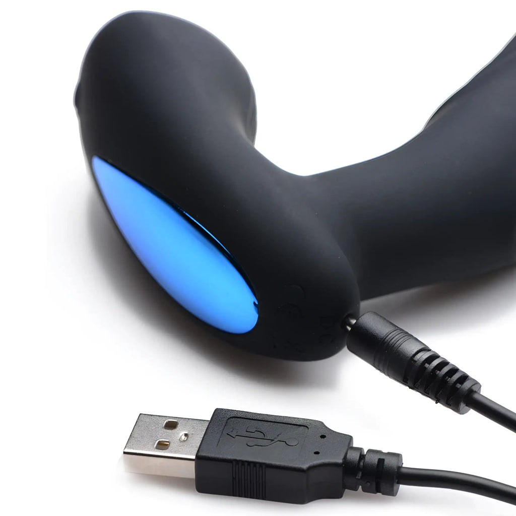 Alpha Pro 7X P-Thump prostate stimulator in matte black with a blue light detail, connected to a USB charging cable.