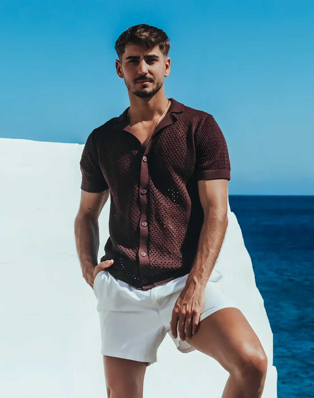 A man wearing a dark brown Amafi knit shirt with short sleeves open collar and textured fabric