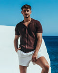 A man wearing a dark brown Amafi knit shirt with short sleeves open collar and textured fabric