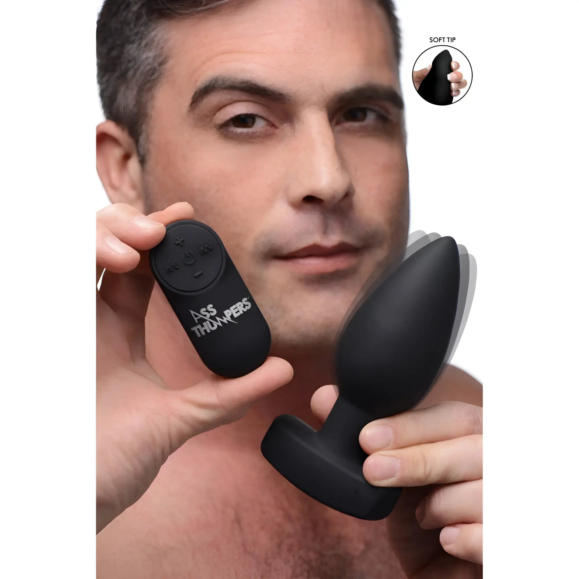 Man holding a smooth, black Ass Thumpers The Taper 10X vibrating butt plug and its matching remote control.