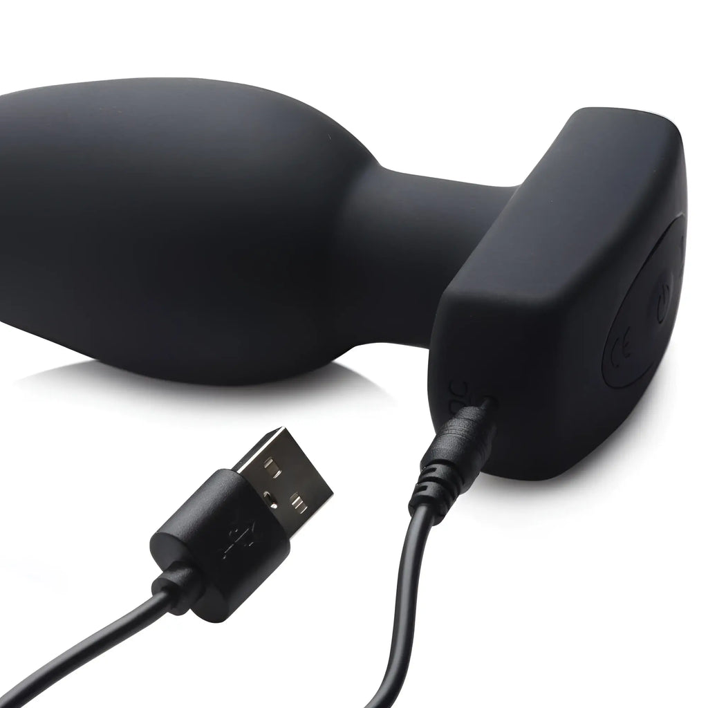 Black silicone Ass Thumpers The Taper vibrating butt plug with a T-shaped base and magnetic USB charging cable.
