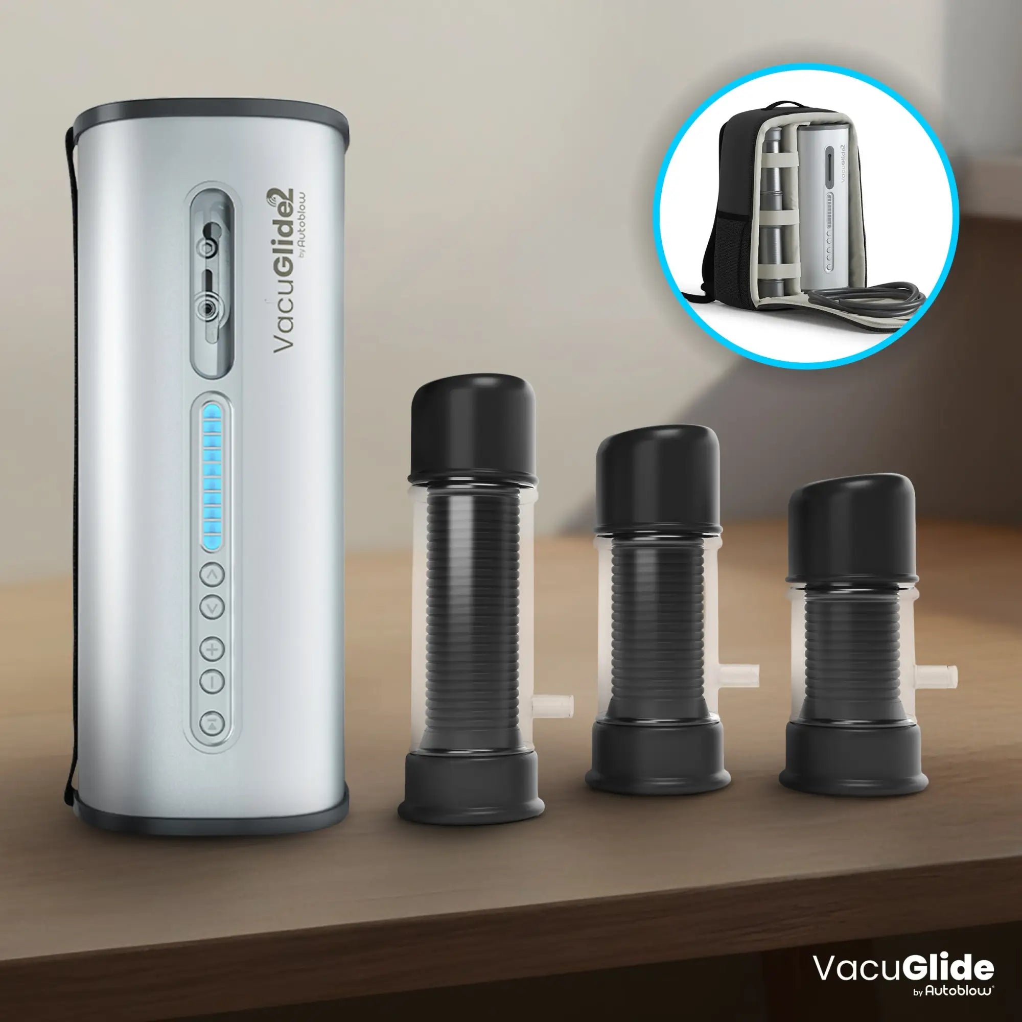 Autoblow VacuGlide 2 silver base unit with three black sleeves and a travel case insert on a wooden table.