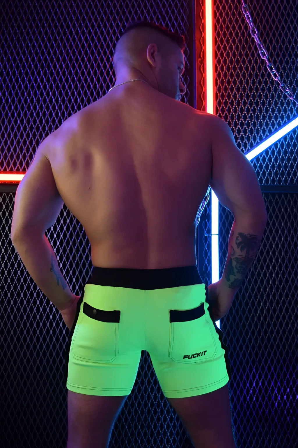 Neon green backpack shorts with black waistband and side pockets featuring a fuckit logo on the lower right leg