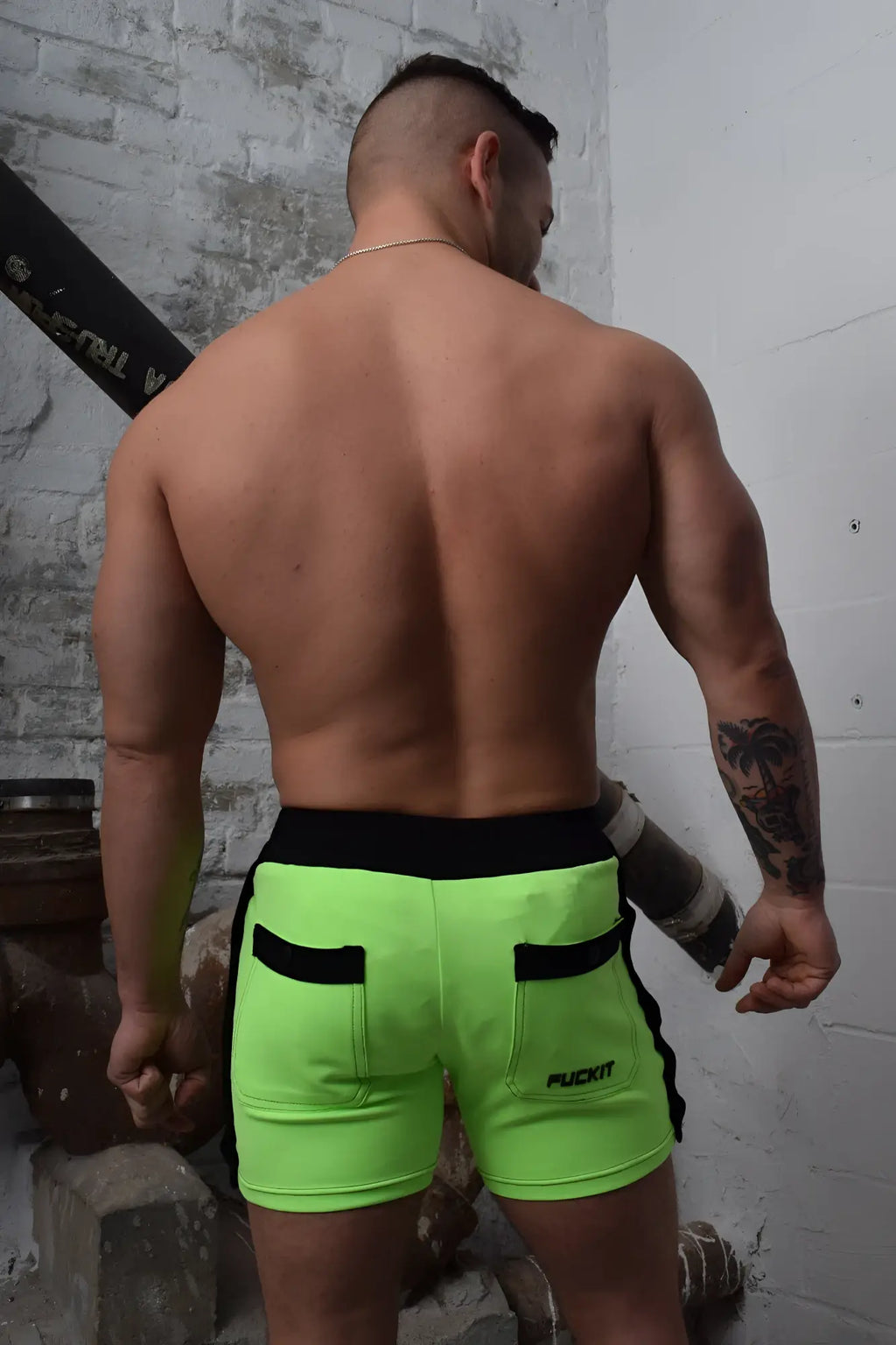 Neon green backpack shorts with black trim side pockets and puckit logo on lower right leg for athletic use